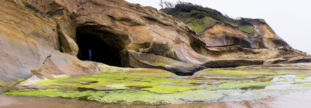 A tiny figure standing in the opening of a huge sea cave on the West Coast of the USA