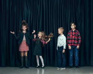 Cute surprised stylish children on dark background. Beautiful stylish teen girls and boy standing...