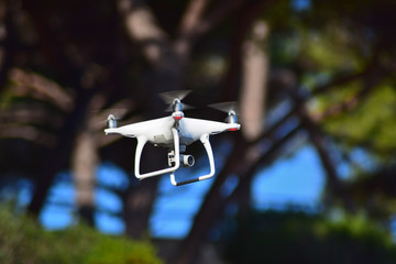 Flying drone with a video camera on a blue sky background.