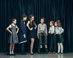 Cute surprised stylish children on dark background. Beautiful stylish teen girls and boy standing...