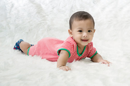 smile baby boy is shooting in the studio. fashion image of baby and family. Lovely baby lie down on a soft white carpet. image for background, wallpaper, copy space, objects, fashion and article