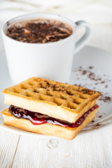 A cup of cocoa and waffles with jam