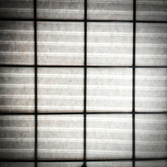 striped fabric behind the black grille, metal grill, cloth behind the grill, dark background, striped fabric