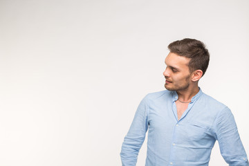 Fototapeta premium Handsome man standing and watching on empty place over the white background