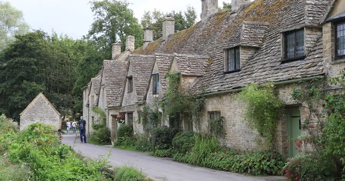 Cotswolds Bibury Village historic rock homes tourists. Historical village with homes businesses built in 1380 AD. Area of Outstanding Natural Beauty. Destination tourism vacation travel.