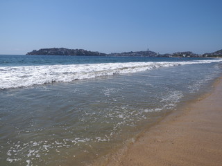 Scenic scenery of sandy beach at bay of ACAPULCO city in Mexico and white waves of Pacific Ocean landscape