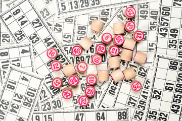 Board game lotto or bingo. Wooden lotto barrels with numbers on background from many lotto cards. Vintage game.