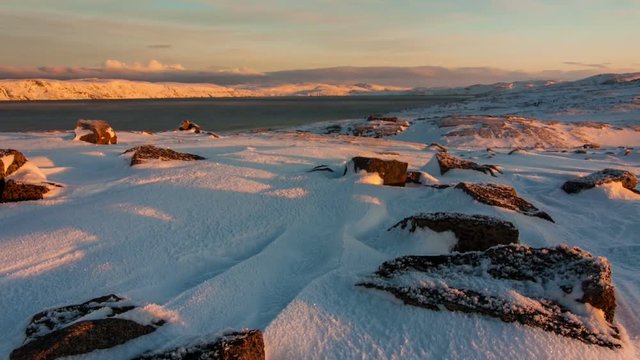 Sunset on the snow-covered shore of the Barents Sea