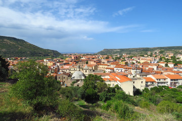 Obraz premium View over the old town of Bosa, the church and typical houses with red roofs surrounded by mountains and the Mediterranean Sea in the distance, Sardinia, Italy
