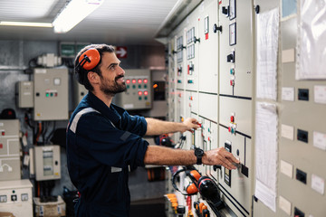 Marine engineer officer in engine control room ECR. Seamen's work. He starts or stops main engine...