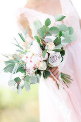 bride's hands hold beautiful bridal bouquet outdoor