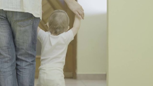 Mother hands holding baby with back,  teaching first steps