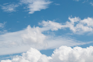 Blue sky with white stratiform and cumulus clouds.