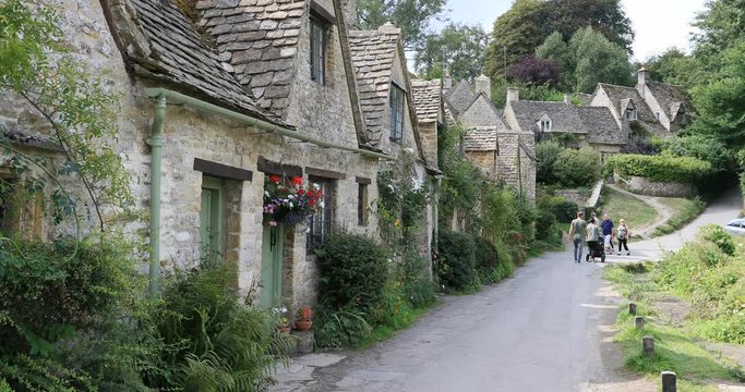 Cotswolds Bibury Village historic rock homes tourists. Historical village with homes businesses built in 1380 AD. Area of Outstanding Natural Beauty. Destination tourism vacation travel.