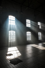 Sunlight shining throuh the windows of an old abandoned industrial warehouse building