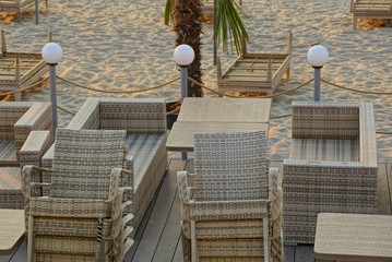 brown wicker furniture stands in the sand on the beach