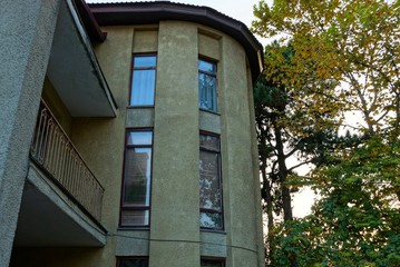 part of a brown house with windows and tree branches with leaves
