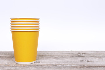 Stack of green paper disposable cups for coffee and nonalcoholic drinks on wooden background