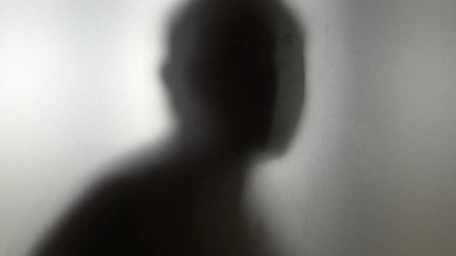 Dancing man behind frosted glass in 4k slow motion 60fps