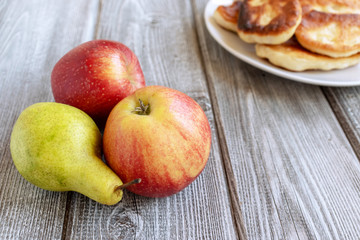 Naklejka na ściany i meble Autumn delicious apples and pear and a plate of pastry on wooden background