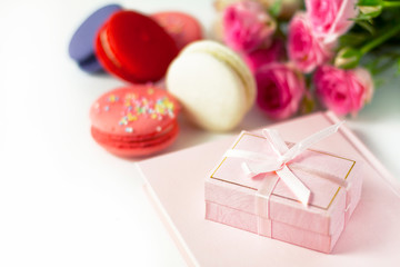  Pink box on a pink book on the background of multi-colored macaroons
