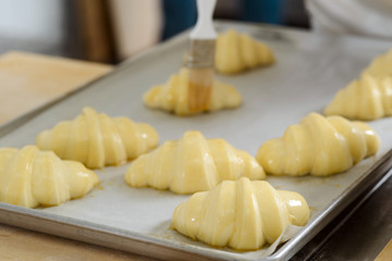 Baker brushing crust of croissants