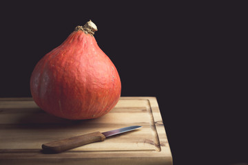 K&uuml;rbis und Messer auf einem h&ouml;lzernen Schneidebrett