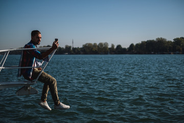 Man taking photo of the river with his mobile phone