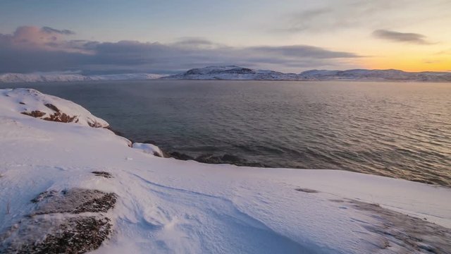 Sunset on the snow-covered shore of the Barents Sea
