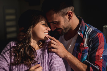 Man hugging girlfriend and touching her lips while she smiles