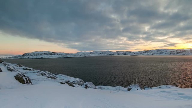 Sunset on the snow-covered shore of the Barents Sea