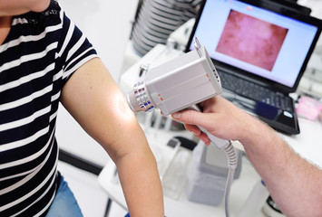 The dermatologist examines the moles or acne of the patient with a dermatoscope. Prevention of melanoma
