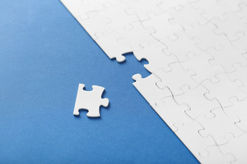 Fototapeta premium On a blue background, white puzzles and the missing piece