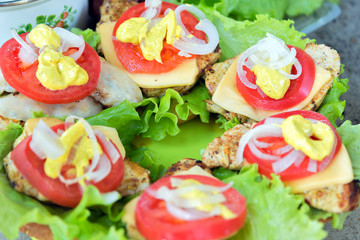 Bbq meat with cheese, tomatoes, onions and lettuce. On a roll and green plastic board