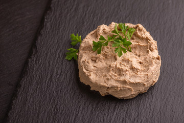 Homemade chicken liver pate with parsley on black slate