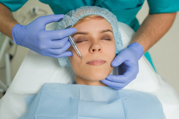 Top view of lips augmentation procedure on a young woman done by a cosmetologist doctor with...
