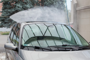 Obraz premium Summer Car Washing. Cleaning Car Using High Pressure Water