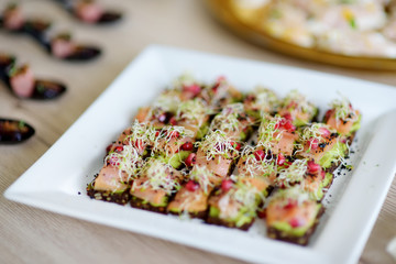 Delicious smoked salmon and avocado mini snacks served on a party or wedding reception.