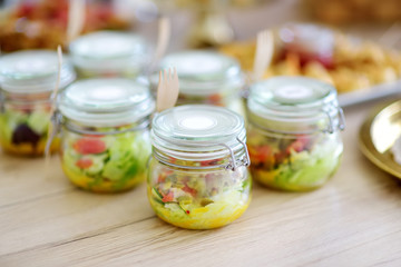 Fresh and delicious vegetable salad served in mini jars on a party or wedding reception.