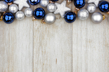 Christmas top border of blue and silver ornaments on a rustic light gray wood background