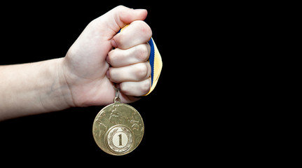 Fototapeta premium Woman hand holding gold medal against black background. Award and victory concept