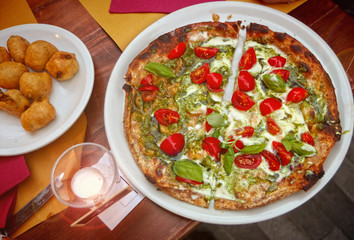 focaccia of Genoa, similar to pizza, topped with soft cheese, cherry tomatoes, pesto sauce and basil seved with deep fried vegetables
