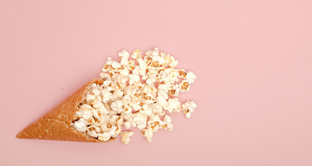 Popcorn in ice cream cones on pink background. Top view