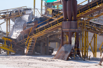 Crushing machinery, cone type rock crusher, conveying crushed granite gravel stone in a quarry open pit mining. Processing plant for crushed stone and gravel. Mining and Quarry mining equipment.