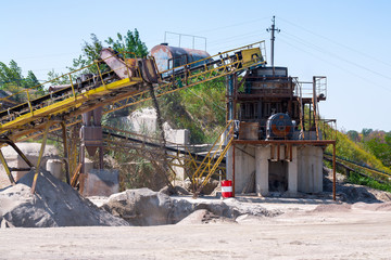 Crushing machinery, cone type rock crusher, conveying crushed granite gravel stone in a quarry open pit mining. Processing plant for crushed stone and gravel. Mining and Quarry mining equipment.