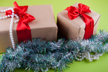 Gift boxes packed with brown craft paper and bright red bows laying near silver decorations on...