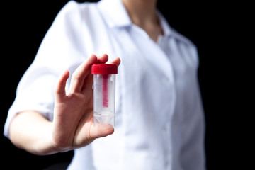 Fototapeta premium Close of woman hands holding sterile sample Container bottle for medical analysis. Health care and medical concept