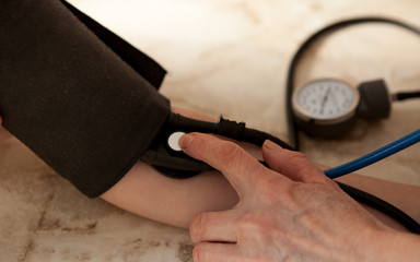 Cropped image of male doctor checking blood pressure of patient at table