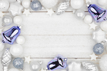 Christmas frame of blue and white decorations, top view over a rustic white wood background
