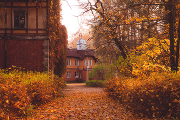 Manor house with trees in autumn colors and fall trees. Old Victorian Haunted House long abandoned to the ghosts. Abandoned house in autumn wood.